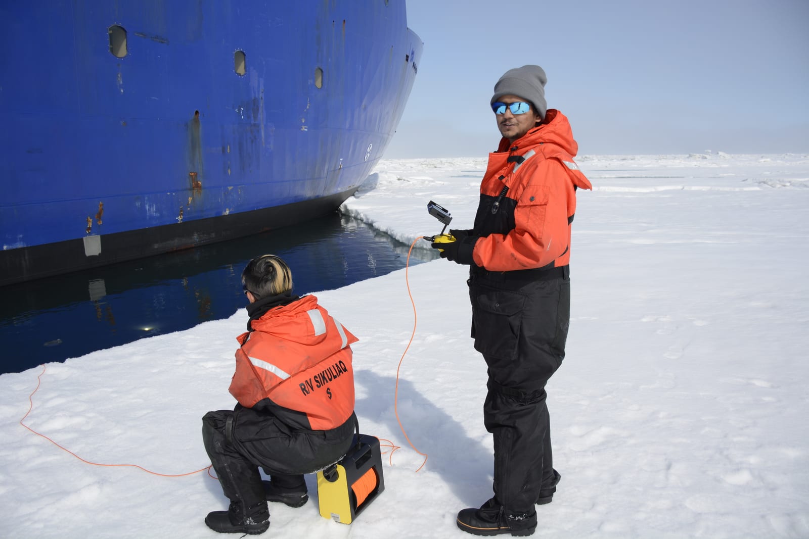 On sea ice beside the RV Sikuliaq, holding a camera controller