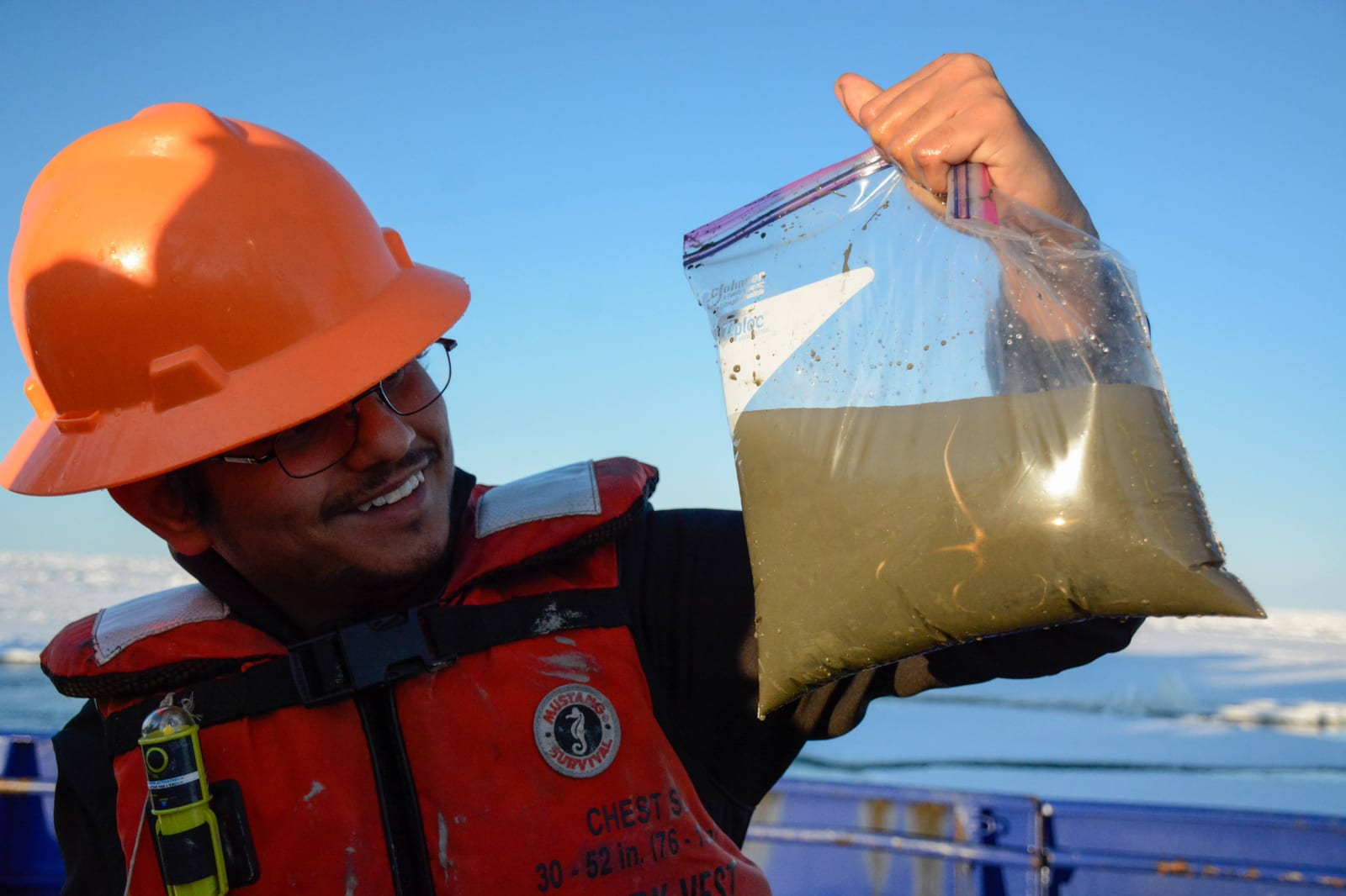 Holding up a sample bag on the deck of a ship